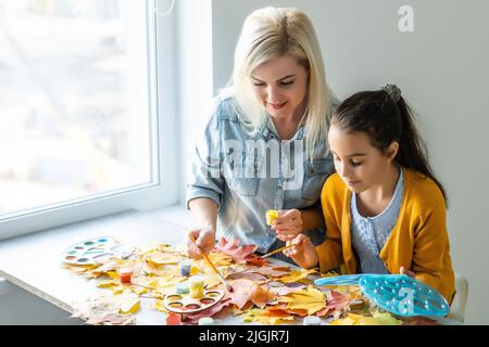 Mutter und Tochter malen Herbstblätter Stockfoto
