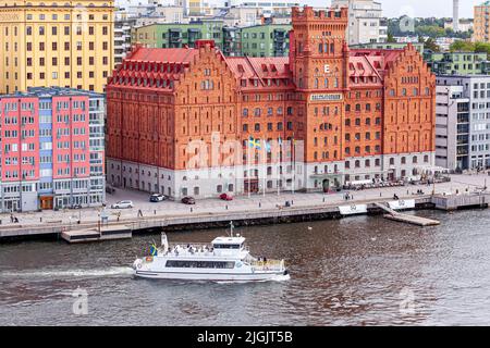 Die Fähre 'Clara' führt am Saltsjoqvarn-Gebäude (ursprünglich eine Mühle, jetzt aber Elite Hotel Marina Tower) in Danviken, Henriksdal im Stockholmer Archi vorbei Stockfoto