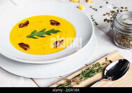 Kürbissuppe mit Samen und Löffel auf dem Tisch Stockfoto