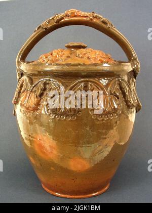 Kruka Pot, sogenannter Gallentopf, mit Deckel und Grab aus Steingut, rot geschnitten, innen und außen grün glasiert. Reliefmuster von Blättern und Blumen. Drehen. Beschädigung des Blattes oben Ornaments mit Punktdekor um den Topf herum. Bodendiam 14 cm, Überdiam 21 cm. Stockfoto