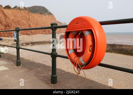 Ein Leben am Geländer auf der Sidmouth Esplanade. Im Hintergrund sind die roten Jurassic-Sandsteinklippen zu sehen Stockfoto