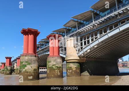 Die Piers der alten viktorianischen Blackfriars Bridge stehen in der Themse neben der aktuellen Eisenbahnbrücke, die den neuen Blackfriars Station unterstützt. Stockfoto