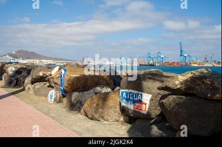 Gemälde auf Steinen im Hafen von Las Palmas de Gran Canary Spanien, im Hintergrund sieht man den Industriehafen Stockfoto