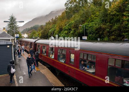 Glenfinnan, Schottland - Oktober 9. 2021: Der berühmte Jacobite Express Zug am Glenfinnan Bahnhof in den Highlands of Scotland, UK. Stockfoto