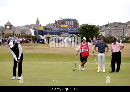 Tiger Woods (links) von Team Woods legt einen Birdie auf das Grün von 2., während Rory McIlroy und Lee Trevino (rechts) während des R&A-Events der Champions auf dem Old Course, St. Andrews, auf den Blick gehen. Bilddatum: Montag, 11. Juli 2022. Stockfoto