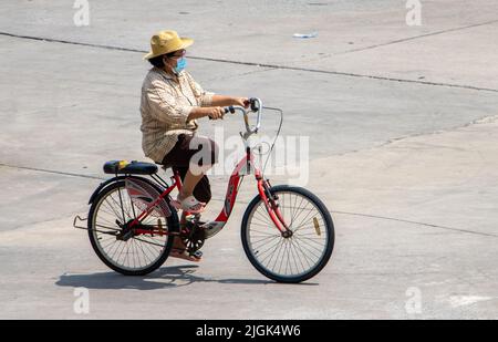 SAMUT PRAKAN, THAILAND, APR 15 2022, Eine Frau fährt auf einem Fahrrad auf der Stadtstraße. Stockfoto
