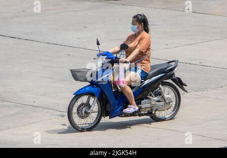 SAMUT PRAKAN, THAILAND, APR 15 2022, Eine Frau mit Gesichtsmaske fährt ein Motorrad Stockfoto