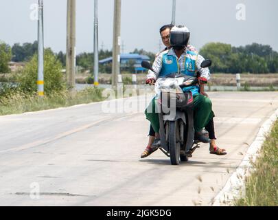 SAMUT PRAKAN, THAILAND, MAI 05 2022, Ein Taxifahrer auf einem Motorrad fährt mit einem Mann. Stockfoto