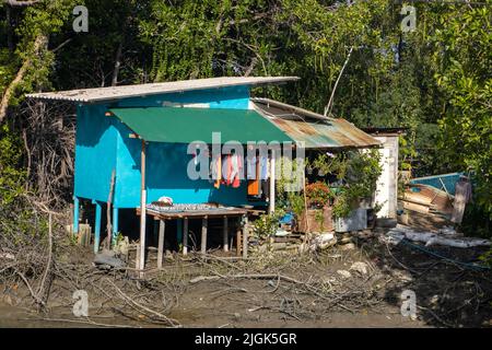 Ein einfaches Haus an einem schlammigen Flussufer. Stockfoto