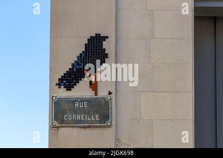 Eine Aaskrähe aus dunklen Mosaikfliesen schmückt eine Hausecke in der Rue Corneille in der Altstadt von Avignon, Frankreich – möglicherweise ein Wortspiel des Straßenkünstlers MifaMosa, da „corneille“ auch das französische Wort für Aaskrähe ist. Seit 2017 hat MifaMosa mehr als 300 solcher thematisch passender Mosaike neben Straßenschildern installiert, darunter in Orléans, Lyon, Montpellier und Lille; drei kleine Punkte neben dem Motiv stellen ihn selbst, seine Mutter und seine Schwester dar. Stockfoto