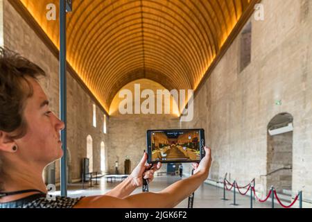 Im Histopad können Sie den Papstpalast in Avignon in seinem mutmaßlichen Originalzustand sehen. Mit dem Histopad, einem interaktiven Tablet-Guide, leuchten die Wände der alten päpstlichen Residenz wieder in Originalfarben, festliche Bänke und Innenräume werden simuliert und geben einen lebendigen Eindruck Stockfoto