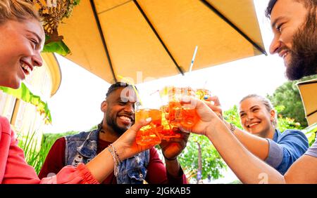 Eine Gruppe junger Leute, die im Sommer in einer Bar bei Getränken Spaß haben - Freunde, die mit einem Coktail jubeln und miteinander lachen Stockfoto