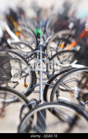 Fahrräder - Objektiv verschwommen. Ein verschwommenes Foto von vielen geparkten Fahrrädern. Nützlich als Hintergrund. Stockfoto