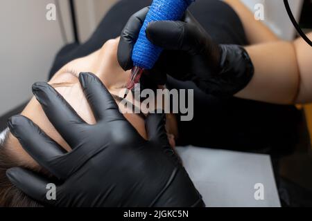 Augenbrauen tätowieren mit Hilfe einer permanenten Make-up Maschine wird von einem Meister durchgeführt Stockfoto