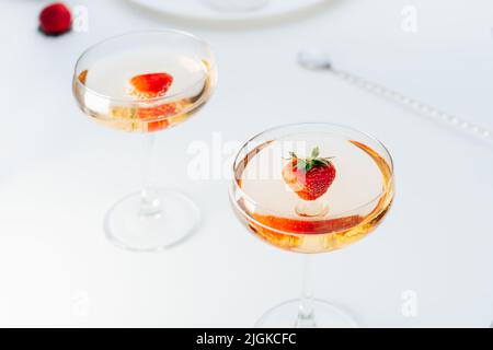 Cocktailgetränke in Cocktailgläsern mit frischer Erdbeere auf dem weißen Tisch. Leichtes Getränk für Sommerparty. Selektiver Fokus, Kopierbereich Stockfoto