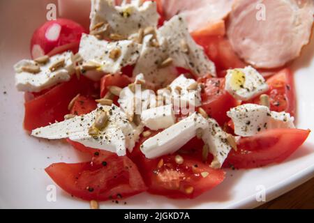 Sommer frischer Bio-Salat mit Tomaten, Zwiebeln, Feta-Käse, verschiedenen Pflanzensamen, Olivenöl und verschiedenen trockenen Gewürzen Stockfoto