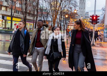 Eine Gruppe von multirassischen Geschäftsleuten überquert gemeinsam die Straße, während sie lächelt Stockfoto