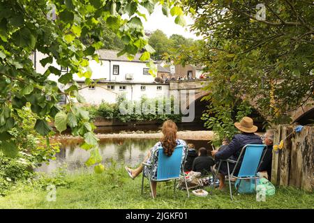 Ein Paar sitzt Liegestühle am Ufer des Flusses Eden, Appleby Horse Fair, Appleby in Westmorland, Cumbria Stockfoto