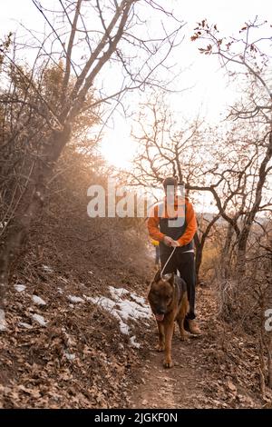 Erstaunliche und gutaussehende männliche Freunde gehen mit ihrem Hund auf dem Weg und lächeln zusammen, während sie reden Stockfoto