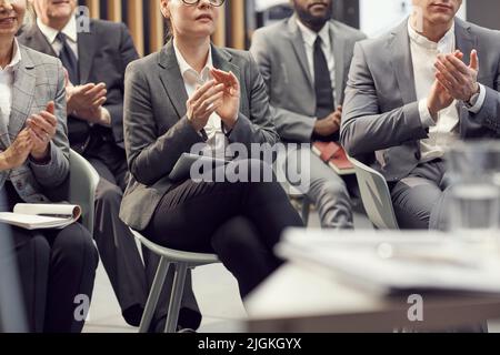Nahaufnahme des Geschäftspublikums, das auf Stühlen sitzt und sich bei der Konferenz mit den Händen zum Sprecher klatscht Stockfoto