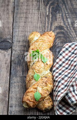 Blätterteiggeflecht, gefüllt mit Hackfleisch auf einem Holztisch Stockfoto