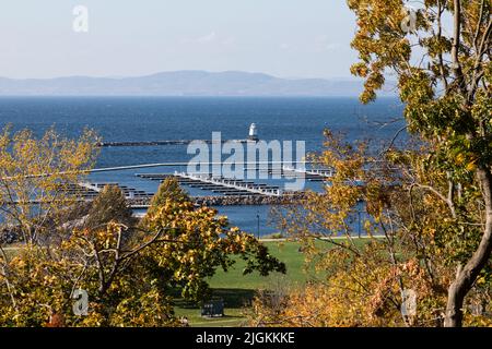 Nahaufnahme des Lake Champlain, der Anlegestellen für Boote und des Leuchtturms aus Burlington, Vermont. Die Adirondack Mountains im Hintergrund. Stockfoto