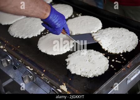 Freiwillige kochen Pfannkuchen bei der jährlichen Spendenveranstaltung des Rotary Club „Pancakes in the Park“ in Santa Fe, New Mexico. Stockfoto