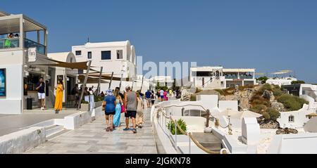 Oia, Santorini, Griechenland - 2022. Juni: Menschen, die in der Stadt Oia an Geschäften vorbeilaufen. Stockfoto