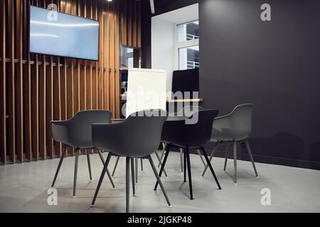 Leerer kleiner Konferenzraum mit grauen Bürostühlen am Plasmabildschirm und Whiteboard Stockfoto