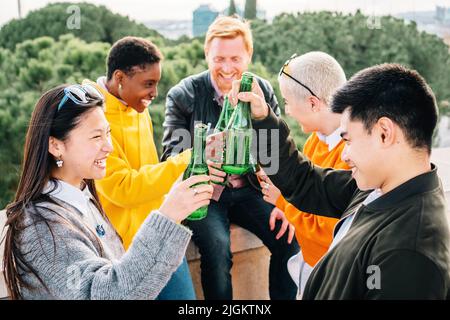 Multiethnische Freunde trinken Bierflaschen und haben gemeinsam Spaß im Freien. Stockfoto