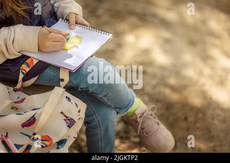 Kleines Mädchen malt im Frühling im Freien blühenden Märchenpark. Kinderzeichnungen. Kreatives Kind. Freude an der Kindheit. Hochwertige Fotos Stockfoto