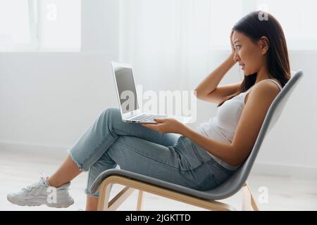 Verärgert unglücklich verwirrt gebräunt schöne junge asiatische Frau schockiert durch Gadget Zusammenbruch zu Hause innen Wohnzimmer. Fernkommunikation, Fernarbeiten Stockfoto