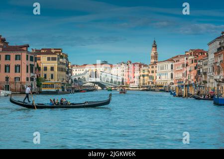 Gondoliere auf seiner Gondel auf dem Canale Grande mit Rialtobrücke im Hintergrund in Venedig, Italien Stockfoto