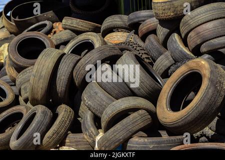 Goiânia, Goiás, Brasilien – 10. Juli 2022: In einem Fachgeschäft stapelten sich viele alte und schmutzige Reifen verschiedener Größen. Gummireifen, gebraucht. Stockfoto