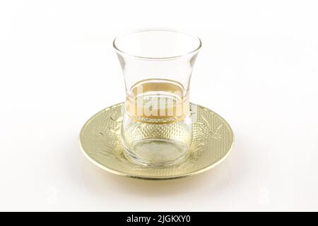 Leeres türkisches Teeglas und Metallplatte isoliert auf Weiß. Traditionell und authentisch Stockfoto