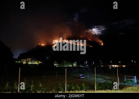 Nago, Trentino-Südtirol, Italien. 11.. Juli 2022. Rauch und Flammen sind am 11. Juli 2022 über der Stadt Nago in Nago, Italien, zu sehen. Seit dem Ausbruch eines Feuers am 10. Juli 2022 in Nago, einer Stadt oberhalb des Gardasees, in Norditalien, brannten über 5 Hektar Wald, da die Dürre und die hohen Temperaturen im ganzen Land anhalten. (Bild: © Aleksander Kalka/ZUMA Press Wire) Stockfoto