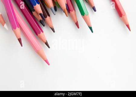 Blick von oben auf einige unordentliche Buntstifte auf einer weißen Oberfläche mit Kopierfläche Stockfoto