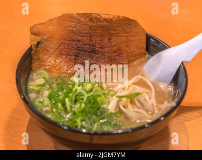Schale einer japanischen Tonkotsu Ramen-Nudeln aus dem Hakata-Viertel in Fukuoka, serviert mit einem Stück gegrilltem Schweinefleisch mit Speck, Negi sca Stockfoto