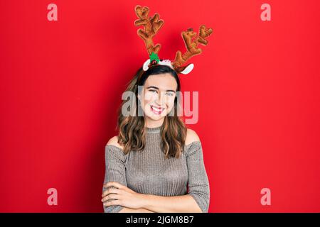 Junge hispanische Mädchen trägt Hirsch weihnachtshut glückliches Gesicht lächelnd mit gekreuzten Armen Blick auf die Kamera. Positive Person. Stockfoto