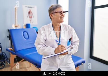 Frau im mittleren Alter, Physiotherapeutin, die in der Reha-Klinik auf die Zwischenablage schreibt Stockfoto