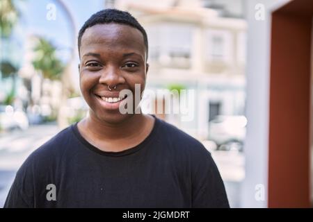 Junge afroamerikanische Transgender lächelt selbstbewusst auf der Straße Stockfoto