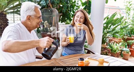 Das hispanische Paar mittleren Alters lächelte und freute sich beim Frühstück auf der Terrasse. Stockfoto