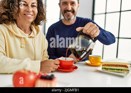 Das hispanische Paar mittleren Alters lächelte fröhlich auf dem Tisch beim Frühstück zu Hause. Stockfoto