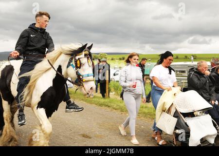 Ein Teenager, der auf einem farbigen Pferd neben dem Campingplatz reitet. Appleby Horse Fair, Appleby in Westmorland, Cumbria, England, Vereinigtes Königreich Stockfoto