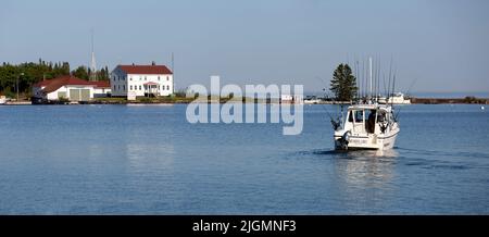 Selektiver Fokus auf Charteranglerboot und die 1928 Station House of U.S. Coast Guard Station North Lake Superior im Hafen von Grand Marais, Minnesota Stockfoto