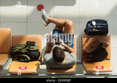 Asiatische Touristen, die ihr Smartphone benutzen und am Flugsteig am Flughafen suvarnabhumi auf einen Flug warten, nachdem sie das Land wieder für eine vollständige Reise geöffnet haben Stockfoto