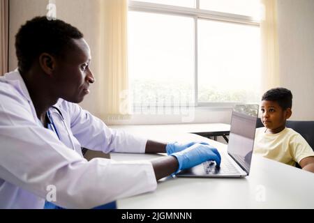 afroamerikanischer Kinderarzt oder Psychologe Arzt im Gespräch mit jungen Patienten im Büro im Krankenhaus. Medizinische und gesunde Lebensweise Konzept Stockfoto