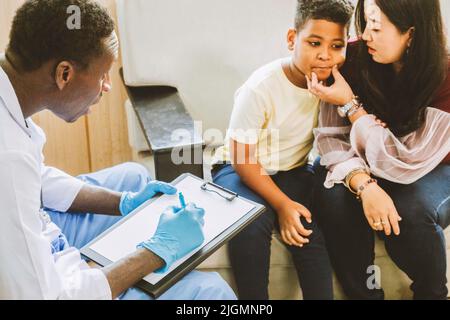 Familienpsychologin. asiatische Mutter und ihr Junge sprechen während der Therapiestunde im Krankenhaus mit dem afroamerikanischen Psychotherapeuten-Arzt. Stockfoto