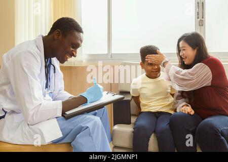 Familienpsychologin. asiatische Mutter und ihr Junge sprechen während der Therapiestunde im Krankenhaus mit dem afroamerikanischen Psychotherapeuten-Arzt. Stockfoto