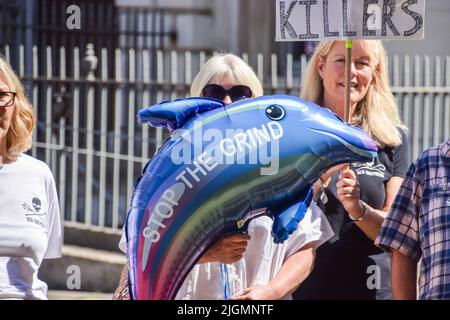 London, Großbritannien. 11.. Juli 2022. Ein Protestler hält während der Demonstration einen delphinförmigen Ballon mit der Botschaft „Stop the Grind“. Sea Shepherd veranstaltete eine Kundgebung vor dem Parlament, als die Abgeordneten eine Petition zur Aussetzung des Handels mit den Färöer-Inseln diskutierten, bis sie die brutale Jagd auf Wale und Delfine, bekannt als „Grind“, beenden. Kredit: SOPA Images Limited/Alamy Live Nachrichten Stockfoto